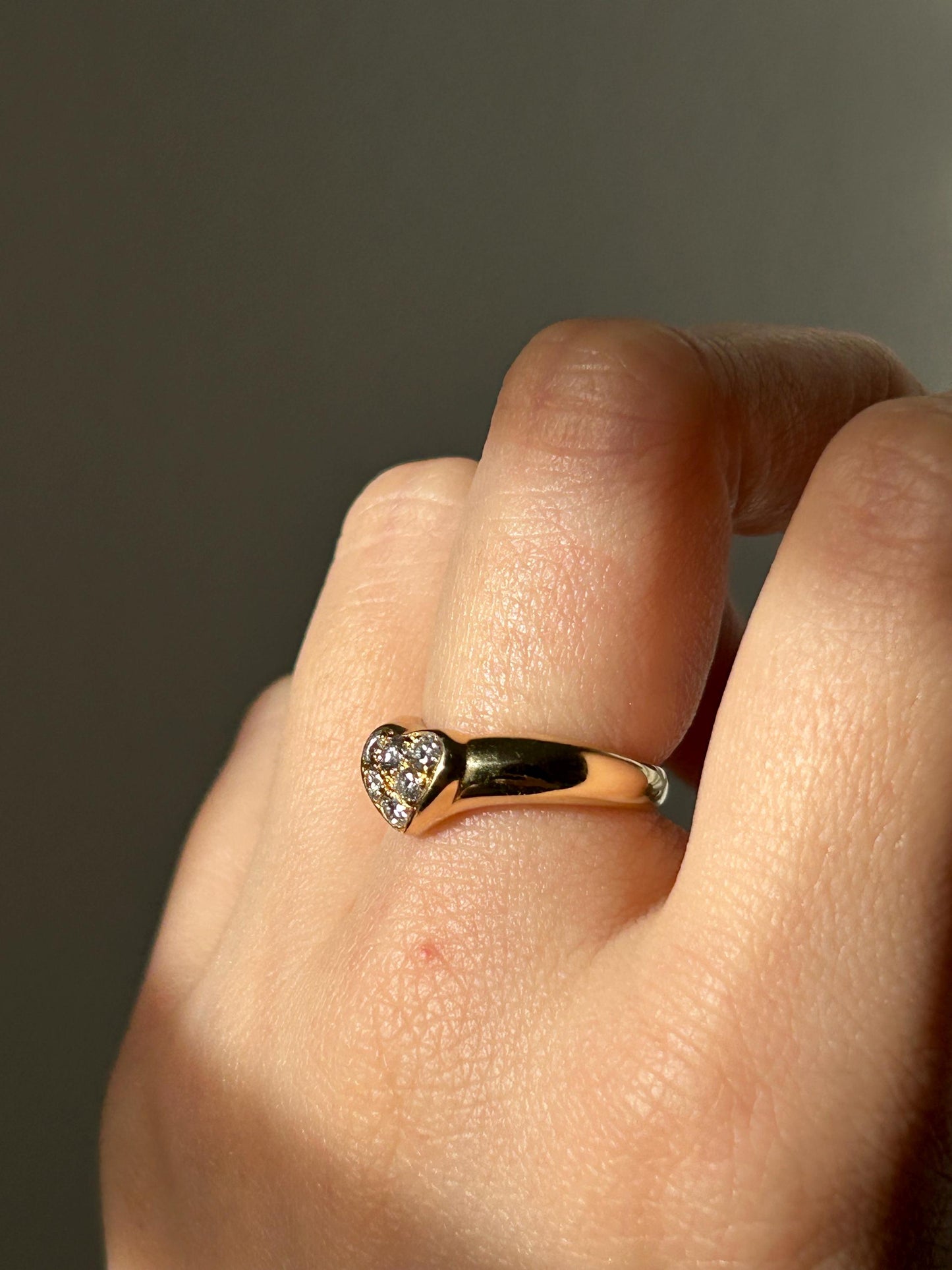 A gold heart-shaped ring with small diamonds stones set in the heart.
