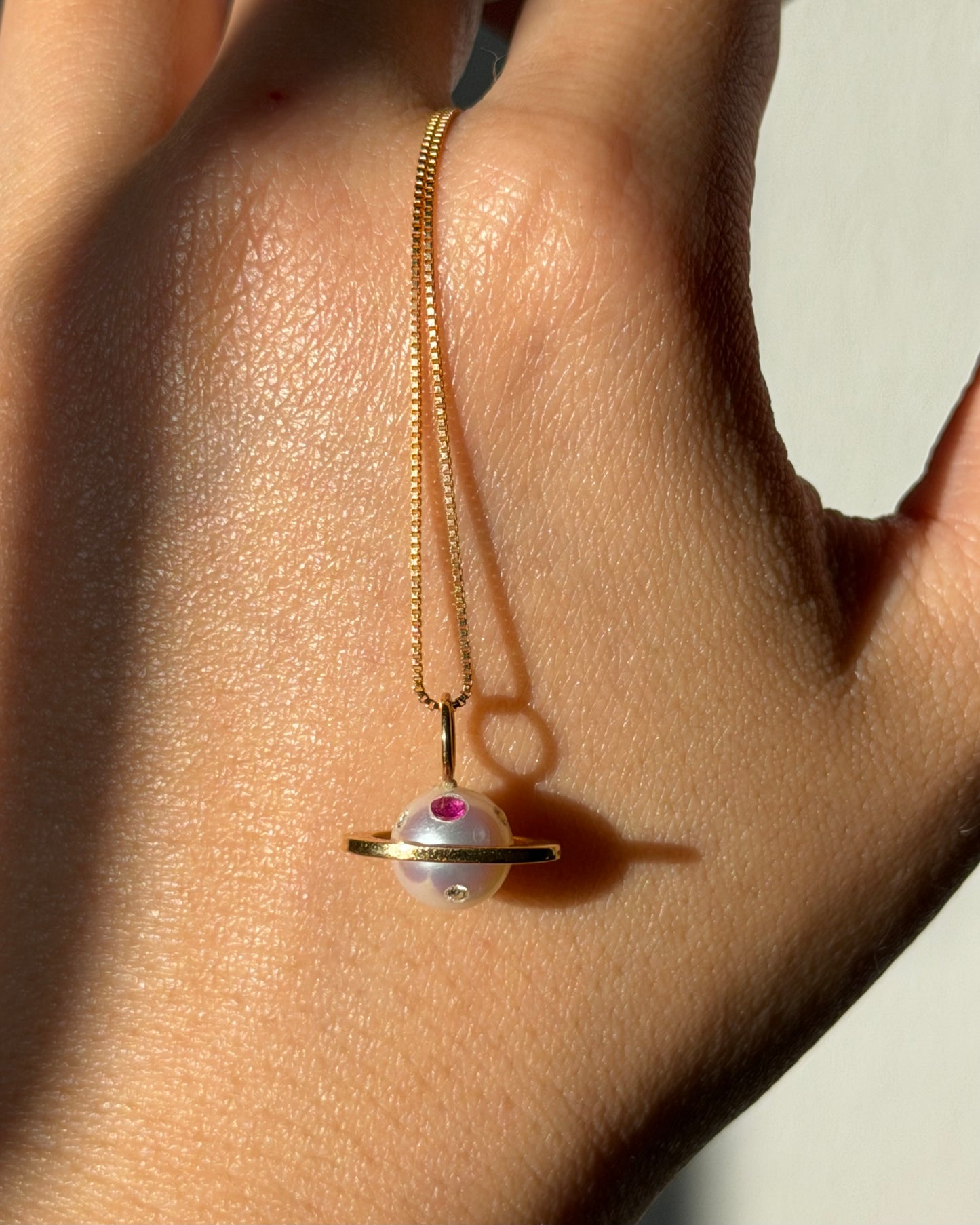 Modern Pre-loved 18k Gold Pearl with Flush Set Ruby and Diamond Saturn Pendant Necklace